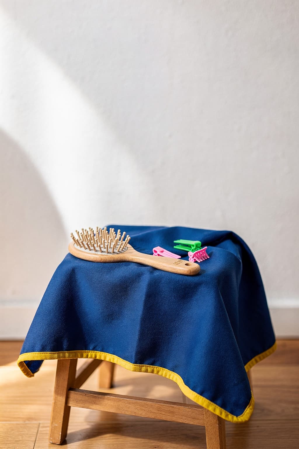 Kleiner Hocker mit blauem Kinderumhang, Bürste und bunten Haarclips